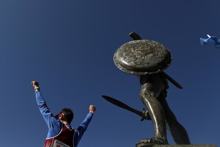 Latvia's Valdis Nilovs celebrates in front of a statue of ancient king Leonidas after completing the Spartathlon race, in Sparta, September 27, 2014. From a daring attempt by a group of friends to one of the most iconic endurance races in the world, the 246-km Spartathlon has defied the downturn in Greek sports, drawing record numbers as ultra marathons become more popular. In a country that has seen international events wiped off the calendar amid a ravaging economic crisis, this race has captured the imagination of runners the world over making it a rare example of how to succeed in difficult financial times. Picture taken September 27, 2014. REUTERS/Alkis Konstantinidis (GREECE - Tags: SPORT ATHLETICS)