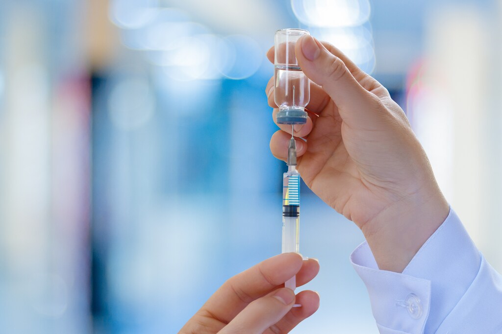 A doctor fills a syringe with vaccine on blurred background. RNA vaccines