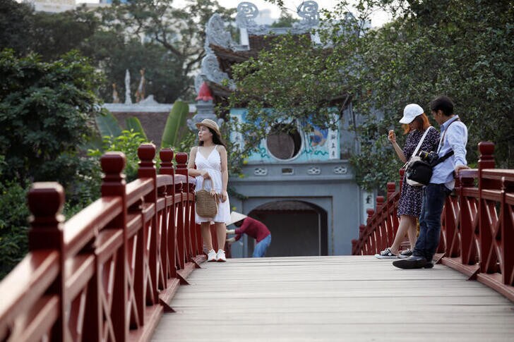 Vietnamese tourists pose for photos on the The Huc bridge at Hoan Kiem lake after the Vietnamese government eased the lockdown following the coronavirus disease (COVID-19) outbreak, in Hanoi, Vietnam May 18, 2020. Picture taken May 18, 2020. REUTERS/Kham