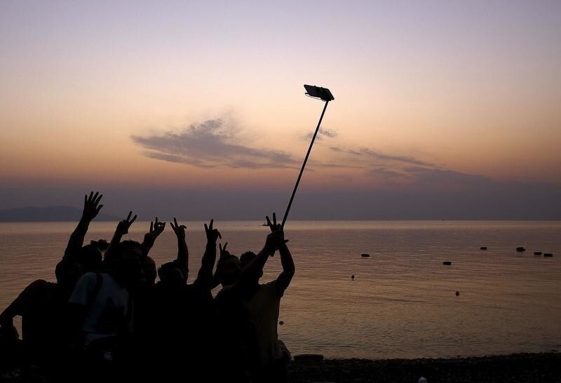Syrian refugees take "selfies" moments after arriving on an overcrowded dinghy at a beach on the Greek island of Kos, after crossing a part of the Aegean sea from Turkey, August 9, 2015. United Nations refugee agency (UNHCR) called on Greece to take control of the "total chaos" on Mediterranean islands, where thousands of migrants have landed. About 124,000 have arrived this year by sea, many via Turkey, according to Vincent Cochetel, UNHCR director for Europe. REUTERS/Yannis Behrakis - GF20000018302