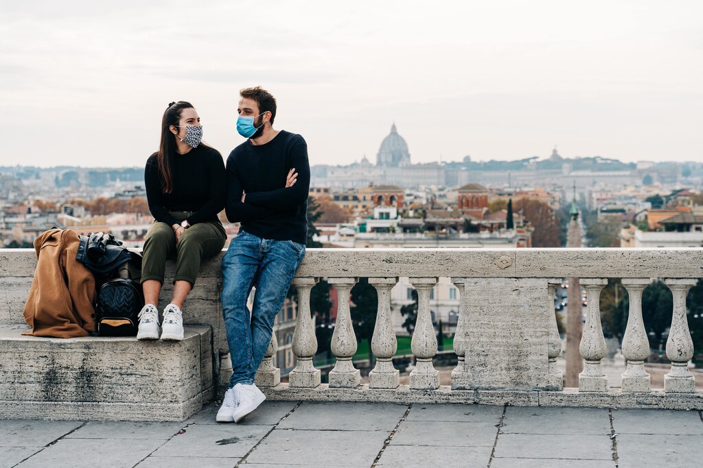 A couple wearing masks in front of view of Rome.
