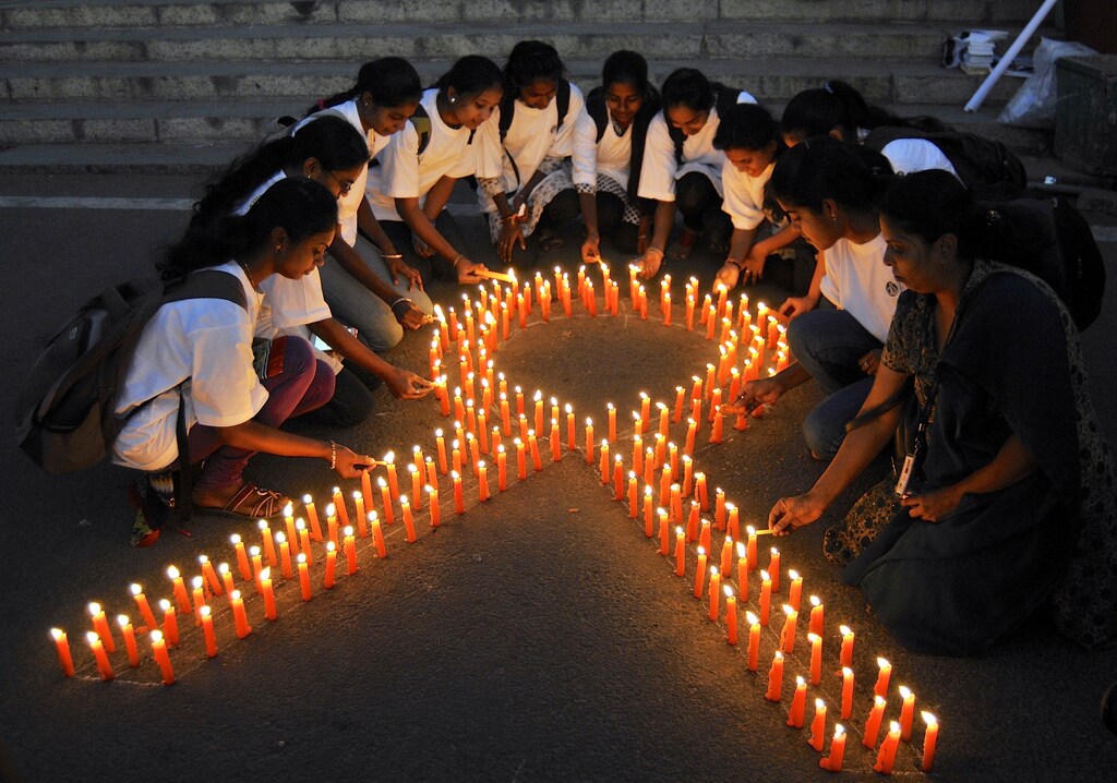 Staff members of a government-run pharmaceutical college light candles arranged in the formation of a ribbon to promote cancer awareness and mark World Cancer Day.