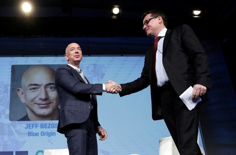 Jeff Bezos, founder of Blue Origin and CEO of Amazon, greets Rodolphe Belmer, CEO of Eutelsat, while speaking about the future plans of Blue Origin during an address to attendees at Access Intelligence's SATELLITE 2017 conference in Washington, U.S., March 7, 2017. REUTERS/Joshua Roberts - RC1193A59390