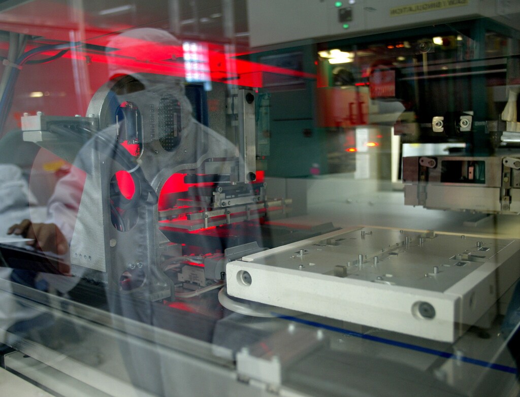 A Filipino manufacturing operator is reflected on an Automatic Mould machine at a Philippine-based semiconductor manufacturing plant in Manila September 20, 2005. The Philippines supplies about 10 percent of the world's semiconductor manufacturing services needs, including mobile phone chips and micro processors, but is facing increasing threat from China. - RTXNSDM