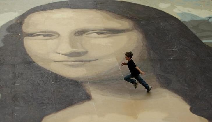 A boy runs across a giant copy of the Mona Lisa as it is unveiled in Wrexham, north Wales, October 28, 2009. The giant version of Leonardo da Vinci's masterpiece measuring 17.5 metres across and 50 times bigger than the original, is an attempt to produce the largest ever reproduction of the painting. REUTERS/Phil Noble (BRITAIN ENTERTAINMENT SOCIETY)
