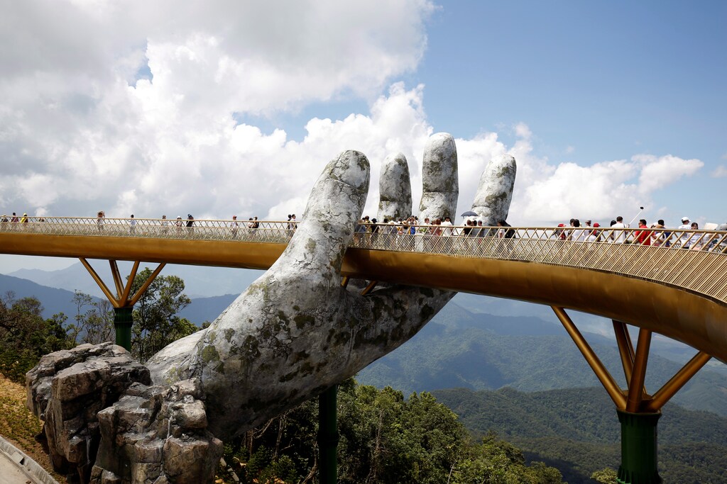 Tourists walk past giant hand structure on the Gold Bridge on Ba Na hill near Danang City, Vietnam August 1, 2018. REUTERS/Kham TPX IMAGES OF THE DAY - RC1474B0A670