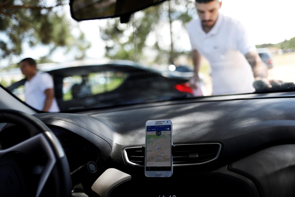 An Uber driver cleans his car as his cell phone shows the queue to pick up passengers departing Guarulhos International Airport in Sao Paulo, Brazil, February 13, 2017. To match Insight UBER TECH-BRAZIL/ Picture taken February 13, 2017. REUTERS/Nacho Doce - RC1C6F8B0150