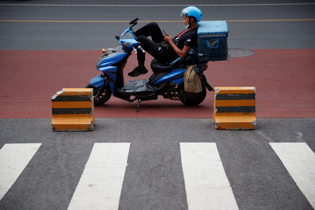 A delivery driver rests on his electric scooter after an outbreak of the coronavirus disease (COVID-19) in Beijing, China, July 8, 2020. REUTERS/Thomas Peter - RC2ZOH9L0STR