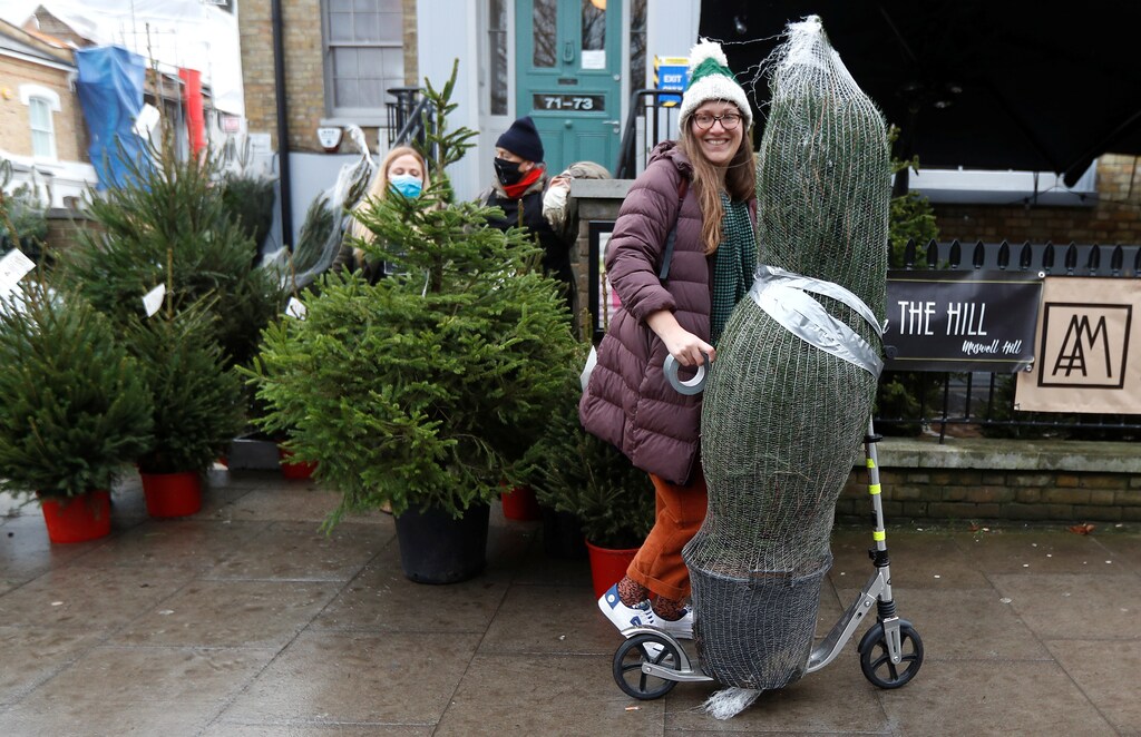 A woman who rented a Christmas tree from Christmas on The Hill carries her tree away on a scooter, in London, Britain, December 12, 2020. Picture taken December 12, 2020.