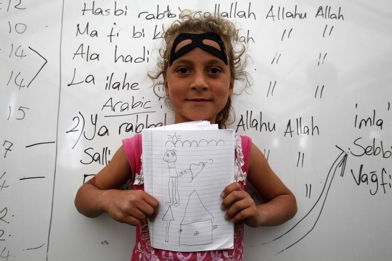 Meriya Senkar, 10, a Syrian refugee, shows a drawing of her dream home during a class at a school for refugee children at Boynuyogun refugee camp in Hatay province near the Turkish-Syrian border April 11, 2012.