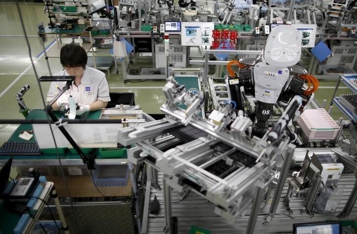 A humanoid robot works side by side with an employee in the assembly line at a factory of Glory Ltd., a manufacturer of automatic change dispensers, in Kazo, north of Tokyo, Japan, July 1, 2015. Japanese firms are ramping up spending on robotics and automation, responding at last to premier Shinzo Abe's efforts to stimulate the economy and end two decades of stagnation and deflation. Picture taken July 1, 2015. REUTERS/Issei Kato