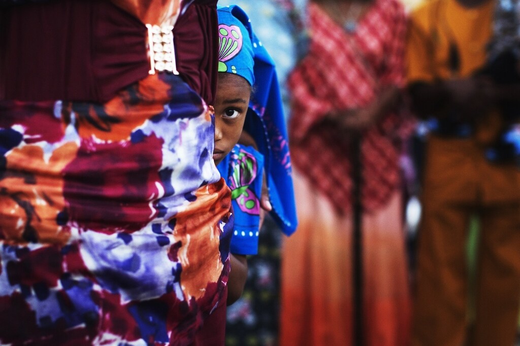A girl from the African Hebrew Israelite community, popularly known as "the Black Hebrews", hides behind an adult during a celebration for the holiday of Shavuot in the southern town of Dimona June 15, 2014. Identifying themselves as African Hebrew Israelites, about 300 African-Americans arrived in 1969 in the sleepy desert town of Dimona, claiming to be descendants of the ancient Israelites and a right to settle in the Jewish state. REUTERS/Finbarr O'Reilly (ISRAEL - Tags: RELIGION SOCIETY TPX IMAGES OF THE DAY) - RTR3TXOZ
