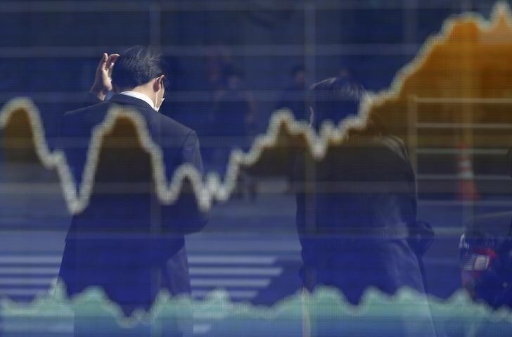 A man is reflected on an electronic board displaying a graph of Japan's Nikkei share average outside a brokerage in Tokyo March 12, 2015. Japan's Nikkei share average posted its biggest daily gain in a month on Thursday as investors chased the market higher before the futures settlement, while hopes that Toyota Motor Corp may increase pay also lifted sentiment. REUTERS/Toru Hanai (JAPAN - Tags: BUSINESS)