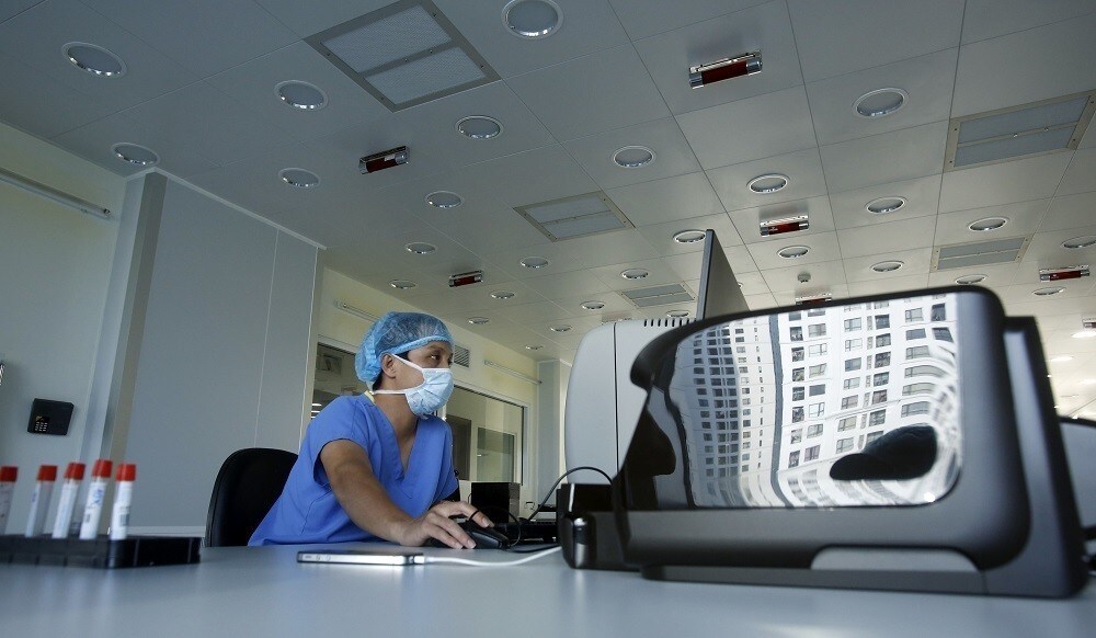 Times City complex is seen reflected on a printer next to a health worker inside a stem cell laboratory at Vinmec hospital in Hanoi September 12, 2014. With Vietnam's public hospitals stretched beyond their limits and private healthcare a fledgling sector, there's billions to be made courting deep-pocketed Vietnamese for medical treatment overseas. Picture taken September 12, 2014. To match VIETNAM-HEALTHCARE/ REUTERS/Kham (VIETNAM - Tags: HEALTH BUSINESS) - RTR4A74Y