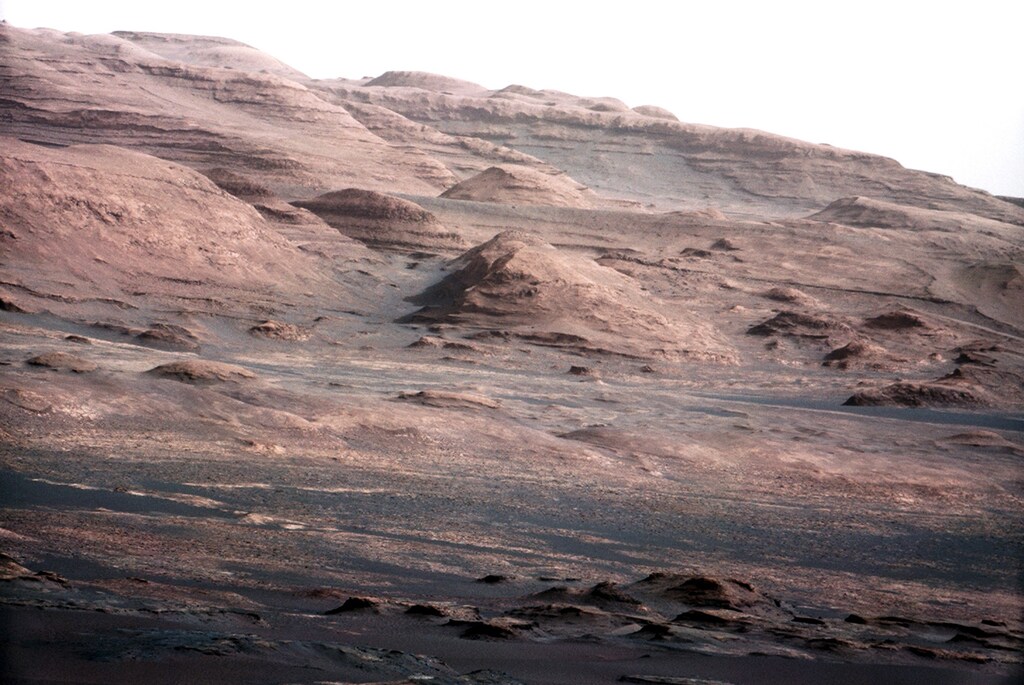 The base of Mars' Mount Sharp - the rover's eventual science destination - is pictured in this August 27, 2012 NASA handout photo taken by the Curiosity rover. The image is a portion of a larger image taken by Curiosity's 100-millimeter Mast Camera on August 23. Scientists enhanced the color to show the Martian scene under the lighting conditions we have on Earth, which helps in analyzing the terrain. REUTERS/NASA/Handout (UNITED STATES - Tags: SCIENCE TECHNOLOGY ENVIRONMENT) THIS IMAGE HAS BEEN SUPPLIED BY A THIRD PARTY. IT IS DISTRIBUTED, EXACTLY AS RECEIVED BY REUTERS, AS A SERVICE TO CLIENTS. FOR EDITORIAL USE ONLY. NOT FOR SALE FOR MARKETING OR ADVERTISING CAMPAIGNS - RTR376EX