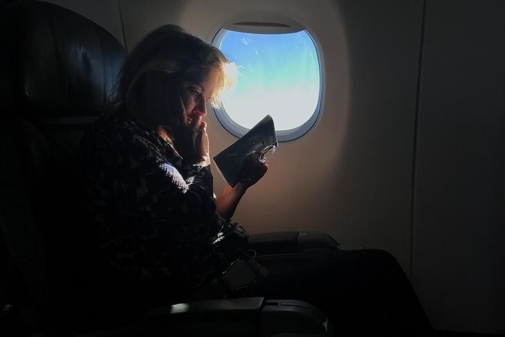 A woman reads while sitting in a business class seat on a flight from New York City to Washington D.C. U.S., December 7, 2017. REUTERS/Carlo Allegri