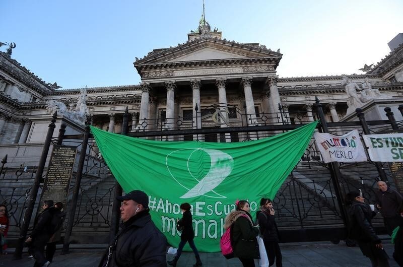 People walk past a giant green flag, a colour which symbolises the abortion rights movement, hanging from the Congress fence in Buenos Aires, Argentina, August 1, 2018.