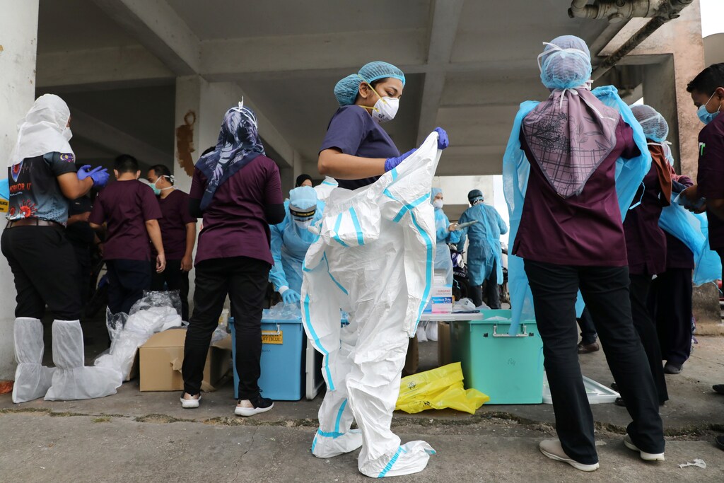 Medical workers put on personal protective equipment before a mass coronavirus disease (COVID-19) swab test in Petaling Jaya, Malaysia October 21, 2020. REUTERS/Lim Huey Teng - RC2YMJ9CKP2T
