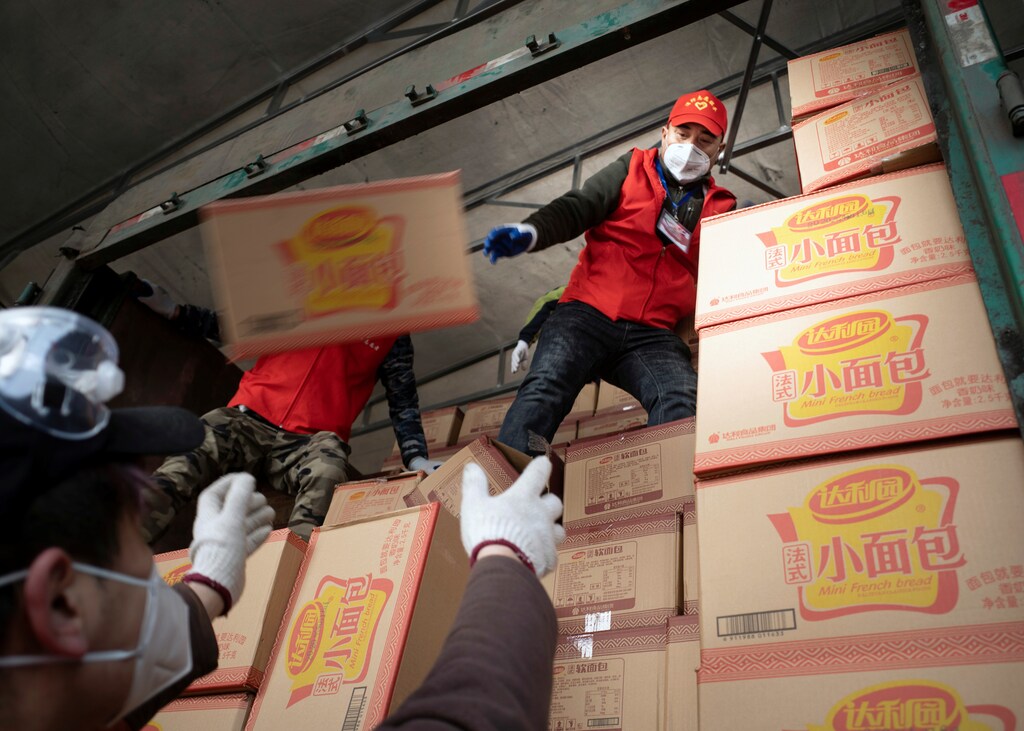 Volunteers wearing face masks unload food supplies delivered from Xiaogan, Hubei province, on a truck following the outbreak of the coronavirus disease (COVID-19), in Suifenhe, a city bordering Russia in China's Heilongjiang province, April 19, 2020. Picture taken April 19, 2020. China Daily via REUTERS ATTENTION EDITORS - THIS IMAGE WAS PROVIDED BY A THIRD PARTY. CHINA OUT. - RC268G9FVOG7