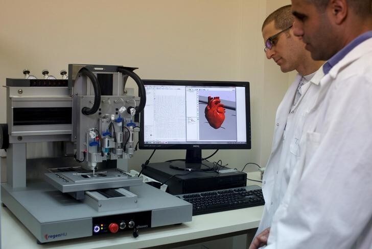 Professor Tal Dvir (R) and a researcher stand next to a 3-D printer during their interview with Reuters about their development of a 3D printed patch comprised of lab-grown heart tissue and nano-electronics that could potentially revolutionize the treatment of heart disease, at a laboratory in Tel Aviv University March 16, 2016. Picture taken March 16, 2016. REUTERS/ Nir Elias