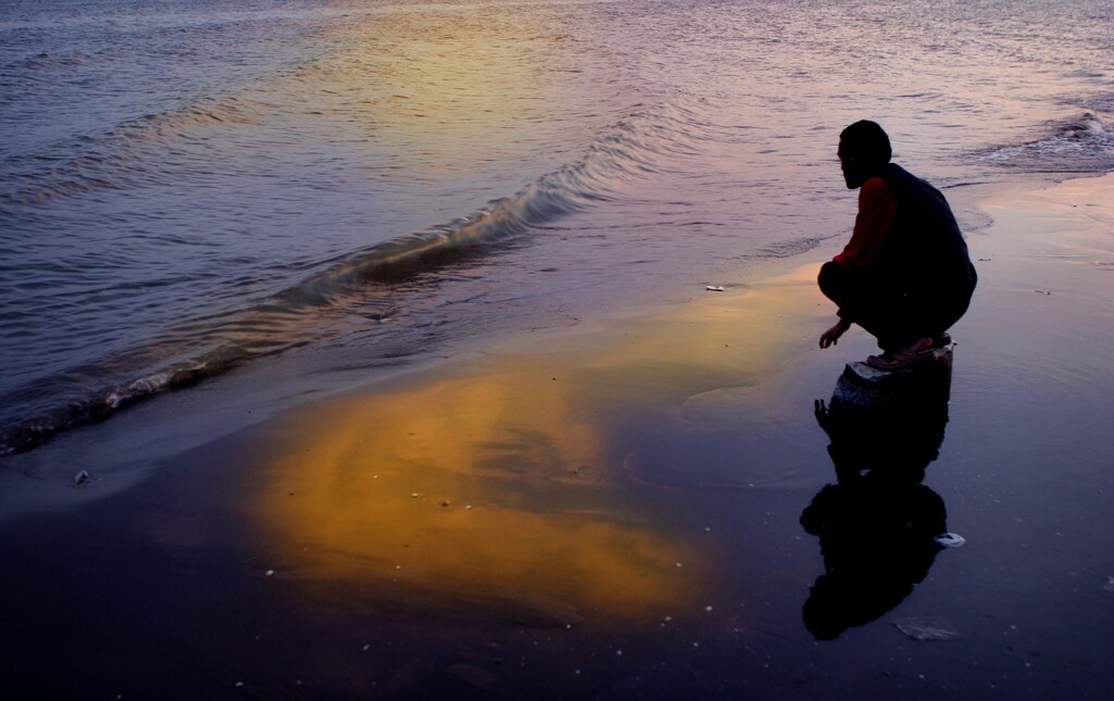 An Iranian man sits on the southern coast of the Caspian Sea during sunrise in Sari, 210 km (130 miles) northwest of Tehran, March 30, 2005. Picture taken on March 30, 2005. REUTERS/Morteza Nikoubazl MN/CCK - RP6DRMUJWOAA
