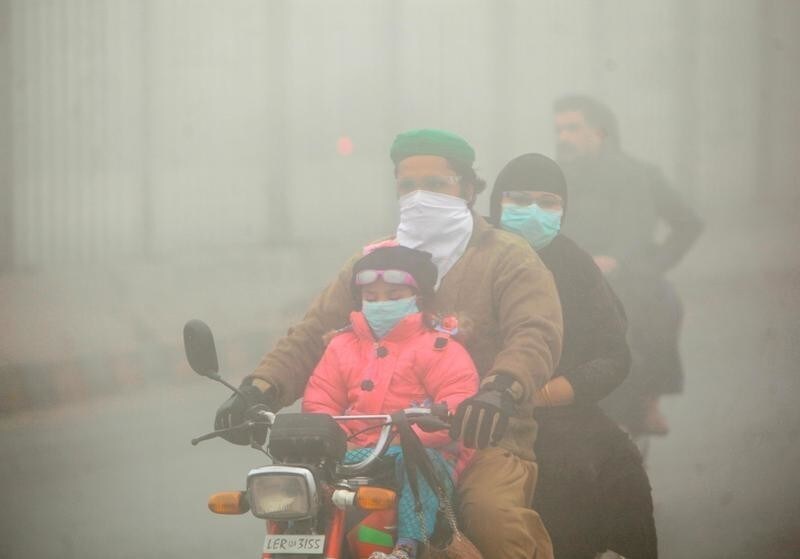 People use face masks to protect themselves from morning smog as they ride on bike along a road in Lahore, Pakistan November 10, 2017. REUTERS/Mohsin Raza - RC1312589480