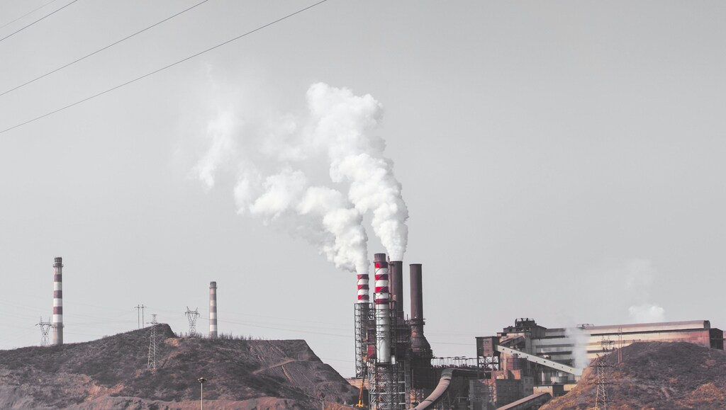Image shows polluting factory chimneys illustrating why it is important to invest in air quality.