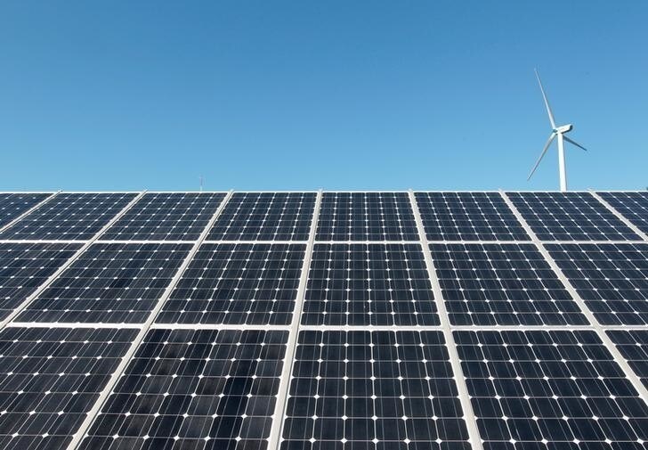 A wind turbine is seen over the panels of a solar power plant of Korea South East Power Co. (KOSEP) in Incheon, in this file photo taken September 30, 2010. REUTERS/Jo Yong-Hak/File Photo