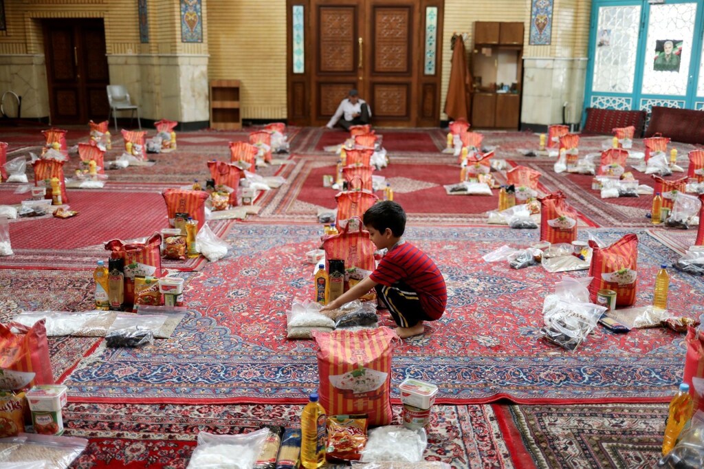 A boy is seen near to prepared food packages to be distributed to poor families during the holy month of Ramadan, following the outbreak of the coronavirus disease (COVID-19), in Tehran, Iran, April 30, 2020. WANA (West Asia News Agency)/Ali Khara via R