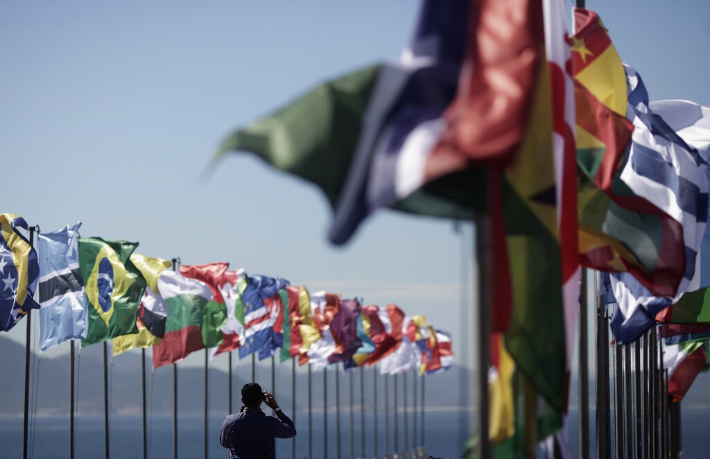 A man takes picture of national flags fluttering at the Copacabana Fort