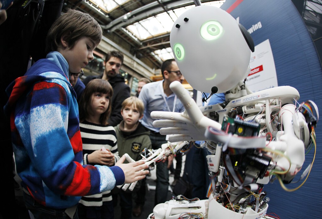 Children interact with the humanoid robot Roboy at the exhibition Robots on Tour in Zurich, March 9, 2013. A project team composed of scholars and industry representatives developed the prototype of the tendon driven humanoid robot Roboy within nine months. Roboy was unveiled to the public today during the exhibition that is marking the 25th anniversary of the Artificial Intelligence Laboratory of the University of Zurich (AI Lab). Picture taken with fish-eye lens. REUTERS/Michael Buholzer (SWITZERLAND - Tags: SCIENCE TECHNOLOGY SOCIETY BUSINESS) - RTR3ERWR