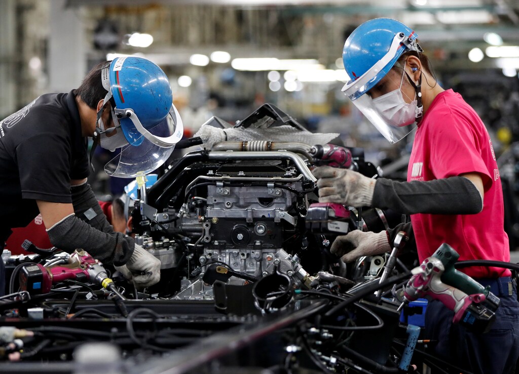 Employees wearing protective face masks and face guards work on the automobile assembly line as the maker ramps up car production with new security and health measures as a step to resume full operations, during the outbreak of the coronavirus disease (COVID-19), at Kawasaki factory of Mitsubishi Fuso Truck and Bus Corp., owned by Germany-based Daimler AG, in Kawasaki, south of Tokyo, Japan May 18, 2020