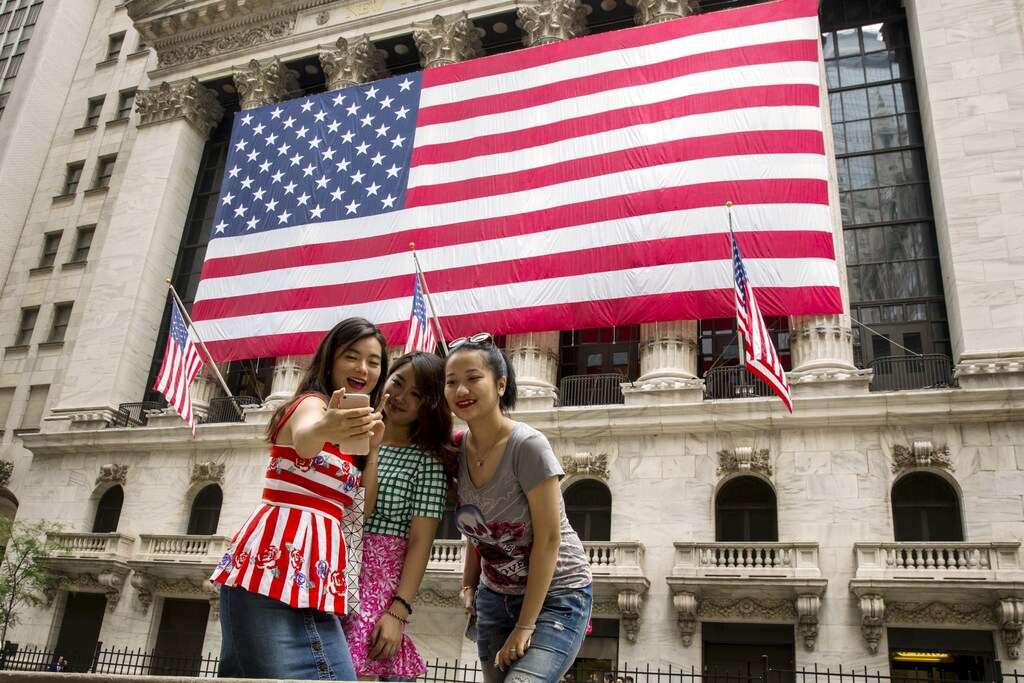 Chinese tourists take photographs of themselves outside of the New York Stock Exchange shortly after the opening bell in New York, July 8, 2015. REUTERS/Lucas Jackson - GF10000152773