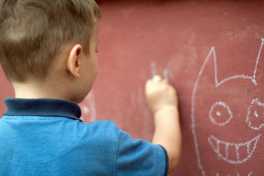 A child drawing on a wall with chalk.