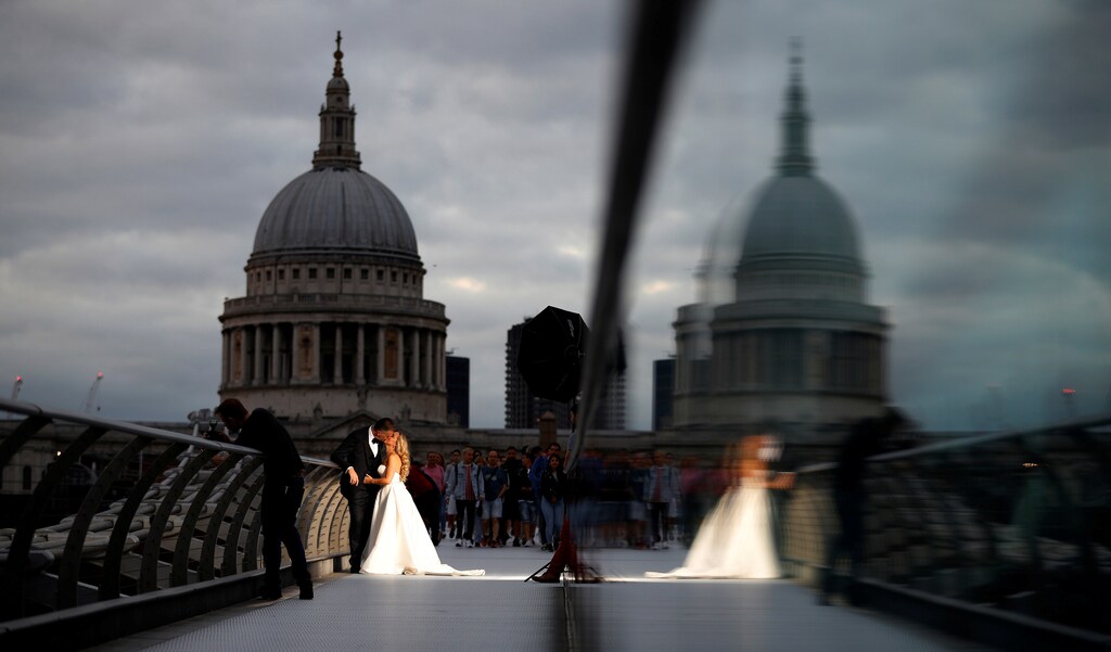 A bride and groom pose for photographs on the Millennium Bridge with St Paul's Cathedral as a backdrop in London, Britain, August 22, 2018. REUTERS/Phil Noble TPX IMAGES OF THE DAY - RC14B26085F0