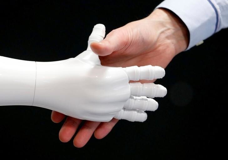 An employee of SoftBank Robotics shakes hands with the Robot Assistant Pepper in Paris, France, March 9, 2018. Picture taken March 9, 2018. REUTERS/Regis Duvignau