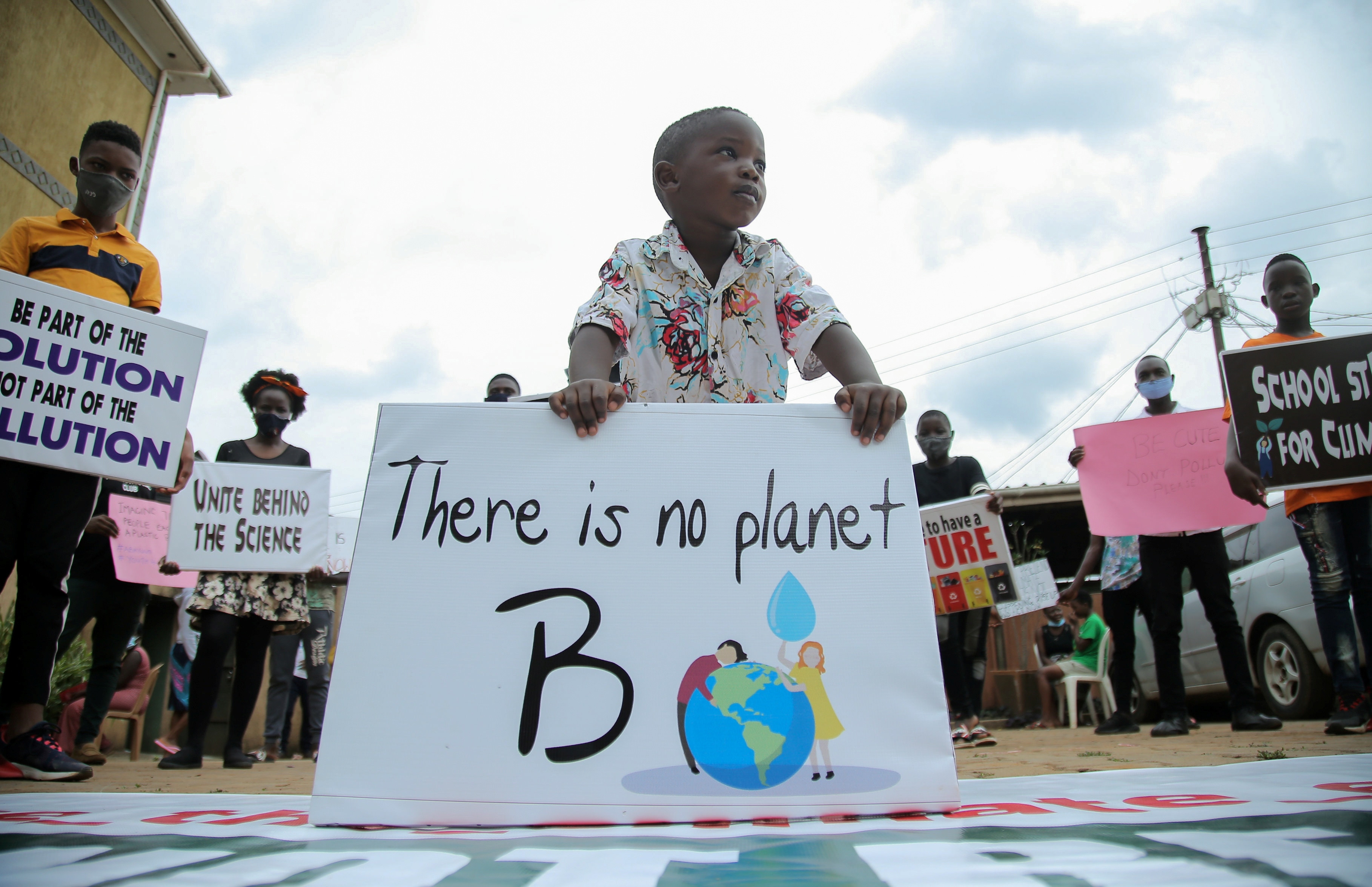 A child stands among Ugandan climate change activists holding placards advocating for climate change as they stand in a formation during a demonstration for the Global Climate Change in Luzira suburb of Kampala, Uganda, September 25, 2020. REUTERS/Abubaker Lubowa - RC2Q5J9EWCKT