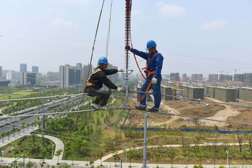 Labourers work on an electricity transmission tower in Chuzhou, Anhui province, China, May 16, 2017. REUTERS/Stringer ATTENTION EDITORS - THIS IMAGE WAS PROVIDED BY A THIRD PARTY. EDITORIAL USE ONLY. CHINA OUT. NO COMMERCIAL OR EDITORIAL SALES IN CHINA. - RTX360S2