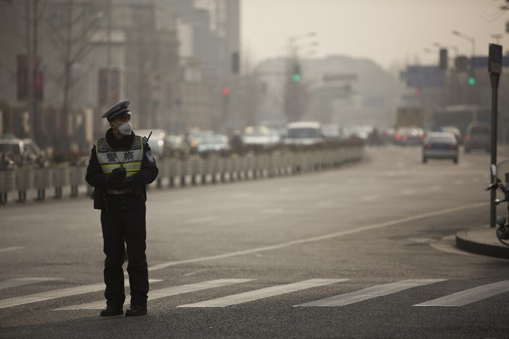 A policeman wearing a face mask stands on a road during a hazy day in Shanghai, January 20, 2014. Chinese steelmakers and power plants are being forced to shop around for higher-quality raw materials to meet tougher air pollution standards, a move that will be a boon for global mining giants that produce premium-grade iron ore and coal. Picture taken January 20, 2014.