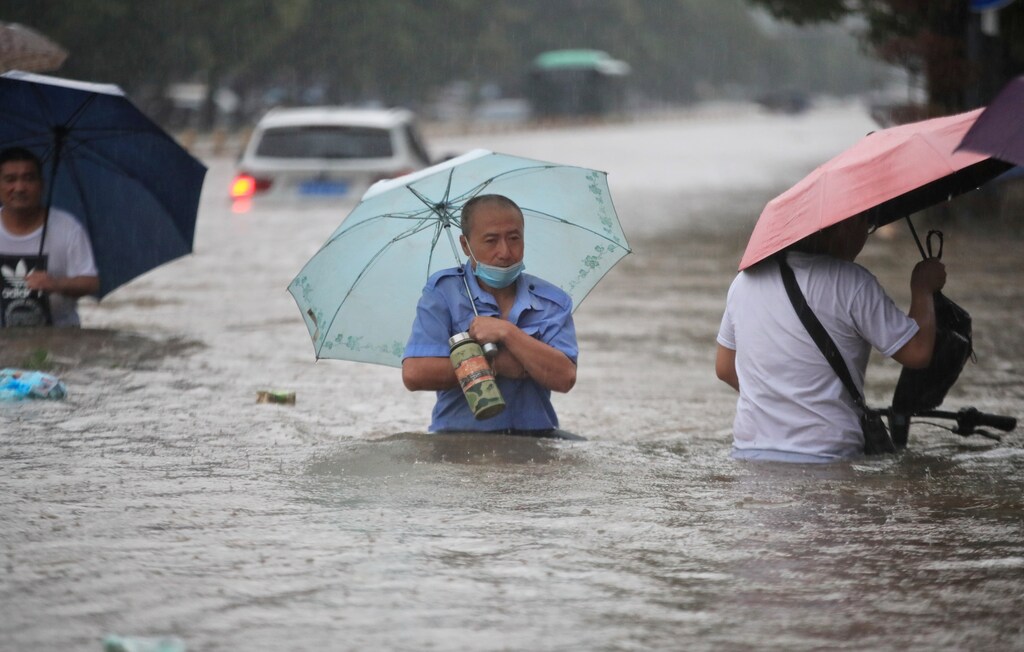 Residents wade through floodwaters on a flooded road amid heavy rainfall in Zhengzhou, Henan province