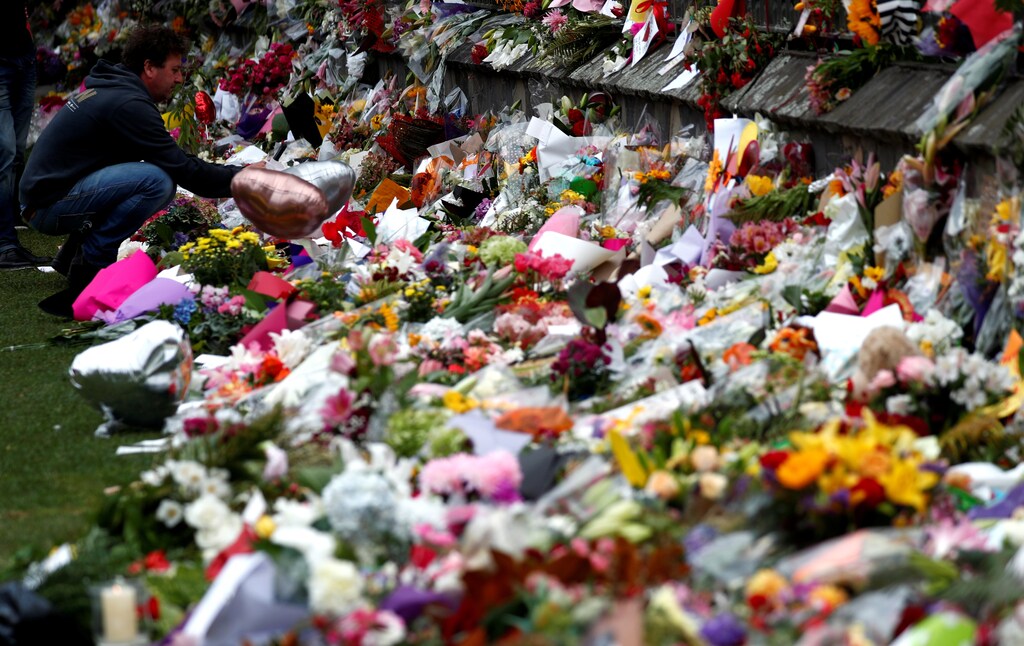 A man places flowers at a memorial site for victims of the mosque shootings at the Botanic Gardens in Christchurch, New Zealand, March 18, 2019. REUTERS/Edgar Su - RC11EE336970