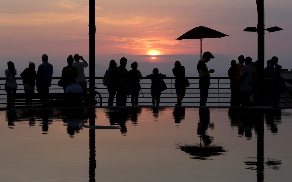 People watch the sunset on a terrace at Larcomar shopping mall in the Miraflores district of Lima April 17, 2015. Larcomar is one of the malls of Chilean company Parque Arauco. The company is planning investments of about $ 730 million through to 2017 to develop various projects in Chile, Colombia and Peru, according to media. REUTERS/Mariana Bazo - RTR4XTBF