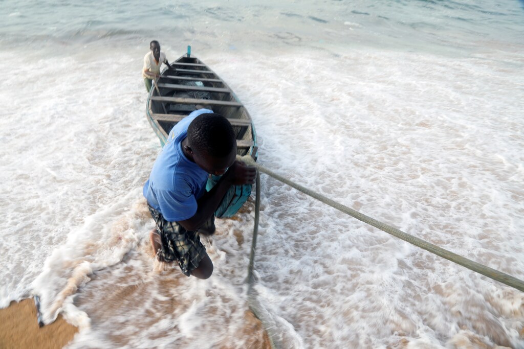 Men pull a boat from the sea at the seashore in a fishing village of Port Bouet in Abidjan, Ivory Coast February 12, 2021.