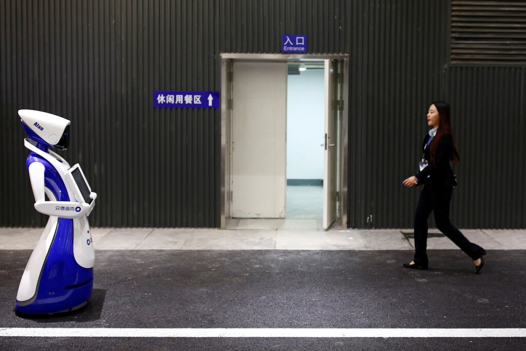 A woman walks past a robot by Robot4U Tech at the WRC 2016 World Robot Conference in Beijing, China, October 21, 2016. REUTERS/Thomas Peter - RTX2PTOW