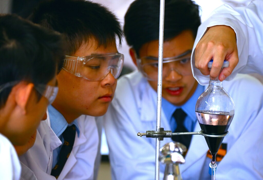 Chemistry students James Wood, Brandon Lee, and Patrick Ngo (L-R) watch Christopher Lai place a glass container into a holder as they prepare to make the compound found in an anti-parasitic medicine used to treat malaria, called Daraprim, at Sydney Grammar School in Sydney, Australia December 2, 2016. REUTERS/David Gray