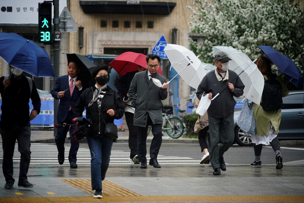 A man holding his mask walks on a zebra crossing among others, amid the spread of the coronavirus disease (COVID-19) in central Seoul, South Korea, April 20, 2020. REUTERS/Kim Hong-Ji - RC268G9J0A8M