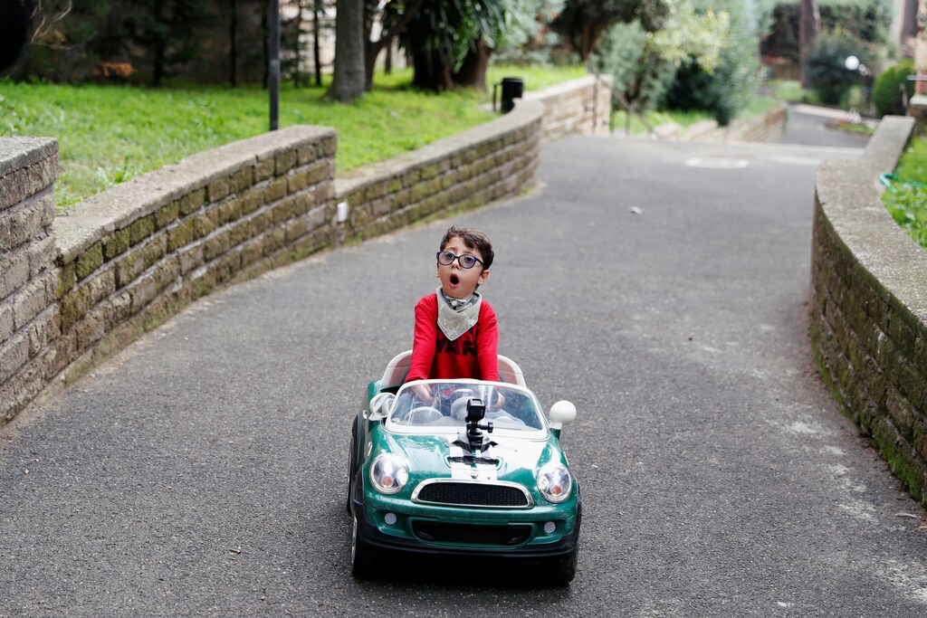 Sirio Persichetti, a 7-year-old Italian with spastic tetraplegia and cerebral palsy drives his toy car in the frontyard of his home in Rome, Italy.