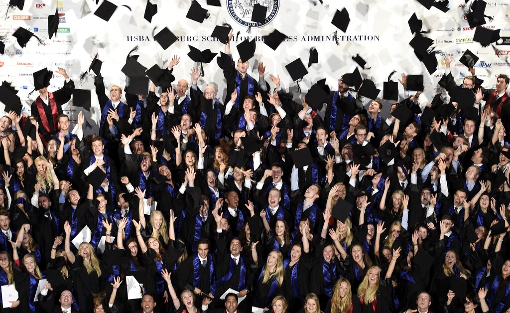 Students throw their mortarboards after their graduation ceremony at the Hamburg School of Business Administration (HSBA) in Hamburg, October 1, 2014. REUTERS/Fabian Bimmer (GERMANY - Tags: BUSINESS EDUCATION SOCIETY) - RTR48JNX