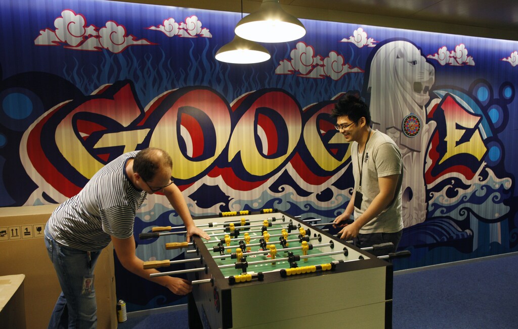 Google's communications manager Robin Moroney (L) plays table soccer with a Google employee at a recreational area of their Singapore office July 8, 2013. Singapore's move to tighten regulation of news web sites, already under fire from bloggers and human rights groups, has attracted criticism from an unexpected quarter - large internet firms with a big presence in the city-state who say the new rules will hurt the industry