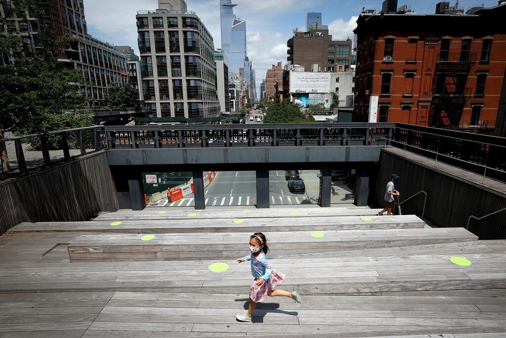 A child wearing a protective face mask plays on a sitting platform painted with social distancing circles on the elevated High Line Park in Manhattan on the first day of the park's re-opening following the outbreak of the coronavirus disease (COVID-19) in New York City, New York, U.S., July 16, 2020. REUTERS/Mike Segar TPX IMAGES OF THE DAY - RC2IUH9RCCYO